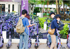 A group of people standing next to scooters Description automatically generated